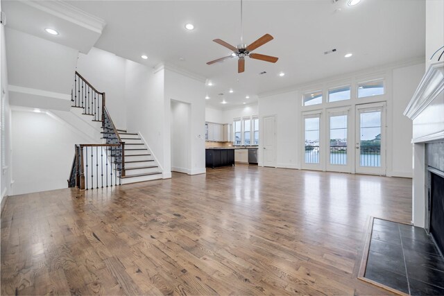 unfurnished living room featuring crown molding, wood finished floors, ceiling fan, recessed lighting, and a fireplace with flush hearth