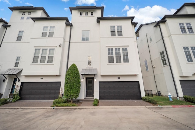 multi unit property with a garage, stucco siding, and decorative driveway