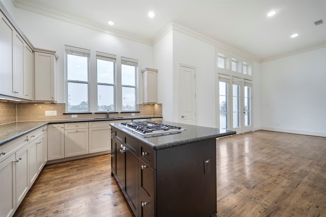 kitchen with crown molding, decorative backsplash, stainless steel gas stovetop, and light wood finished floors