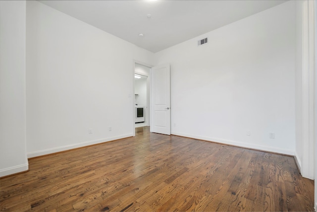 spare room featuring baseboards, wood finished floors, and visible vents