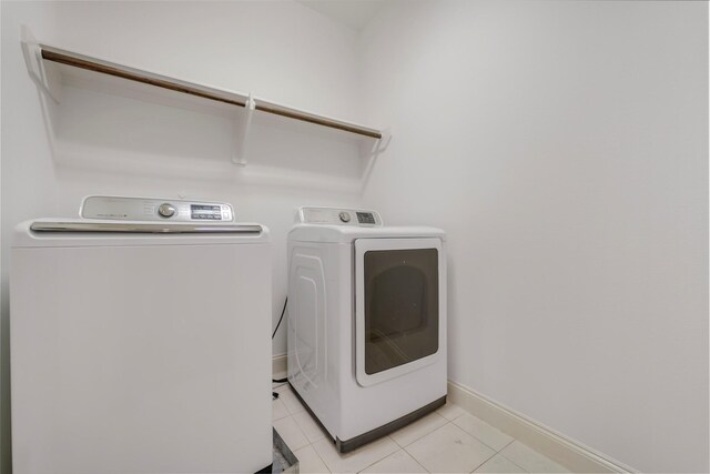 laundry area featuring light tile patterned floors, laundry area, washing machine and dryer, and baseboards