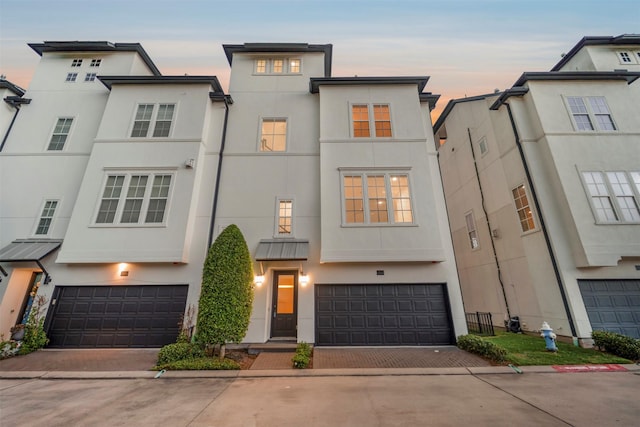 view of property with an attached garage, stucco siding, and driveway