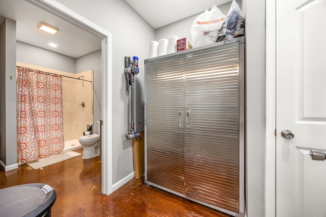 bathroom with concrete floors, baseboards, toilet, and tiled shower