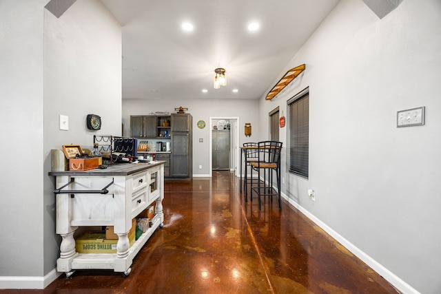 corridor featuring recessed lighting, concrete flooring, and baseboards