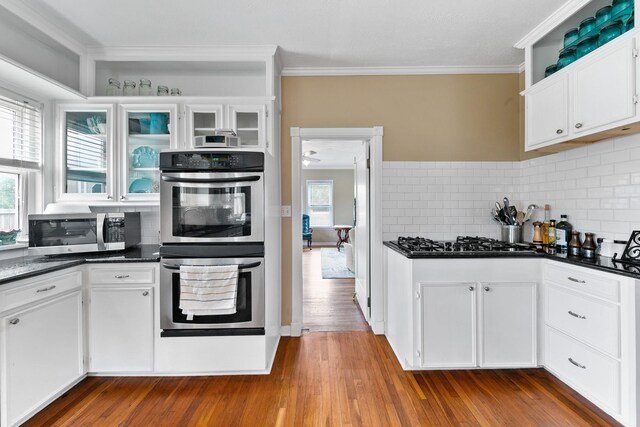 kitchen featuring stainless steel appliances, dark countertops, and crown molding