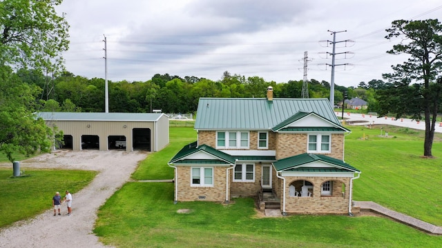 exterior space featuring a front lawn, an outbuilding, metal roof, gravel driveway, and a standing seam roof