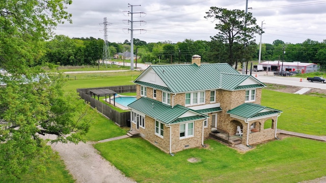 back of house with a yard, a chimney, a standing seam roof, and metal roof
