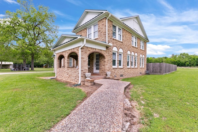 traditional-style home featuring fence, covered porch, brick siding, and a front yard