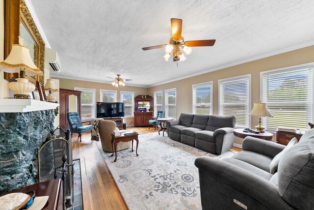 living room with light wood-type flooring, a wall mounted AC, a textured ceiling, and ceiling fan
