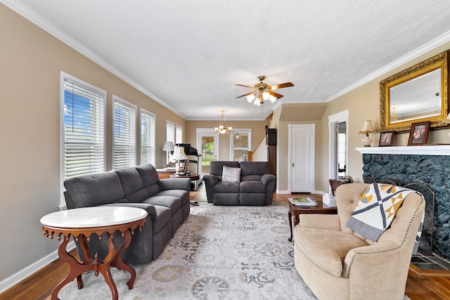 living area featuring wood finished floors, a premium fireplace, crown molding, baseboards, and ceiling fan with notable chandelier