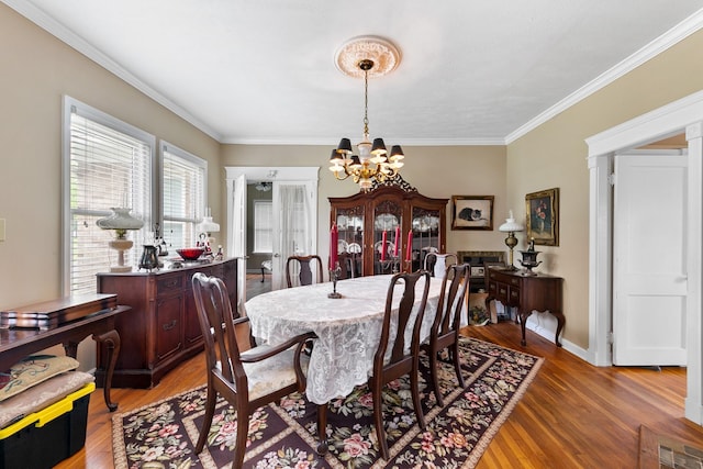dining room featuring visible vents, ornamental molding, light wood-type flooring, baseboards, and a notable chandelier