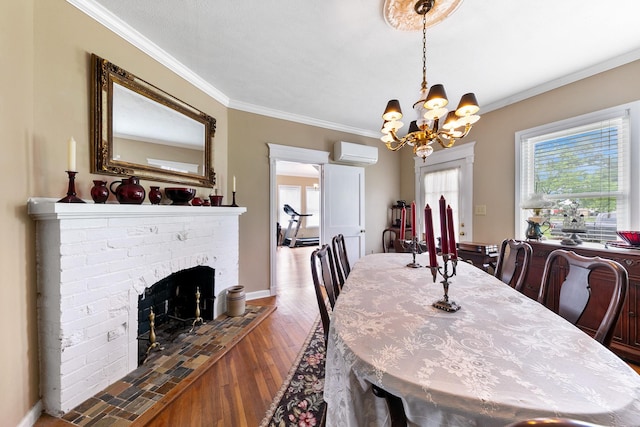 dining room with crown molding, wood finished floors, a wall mounted AC, an inviting chandelier, and a brick fireplace