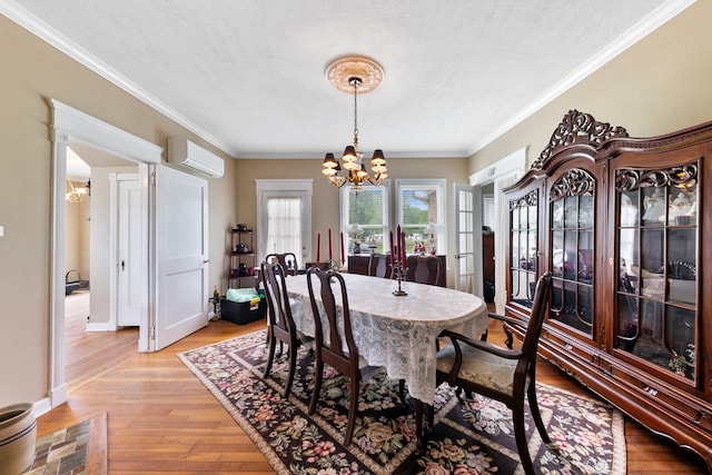 dining space with light wood-style floors, a wall mounted air conditioner, a textured ceiling, and an inviting chandelier