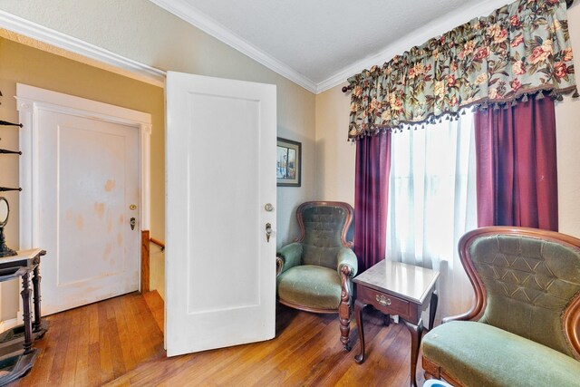 living area with an upstairs landing, lofted ceiling, ornamental molding, and wood finished floors