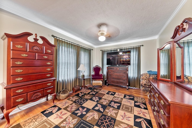 living area with wood finished floors, a textured ceiling, and crown molding
