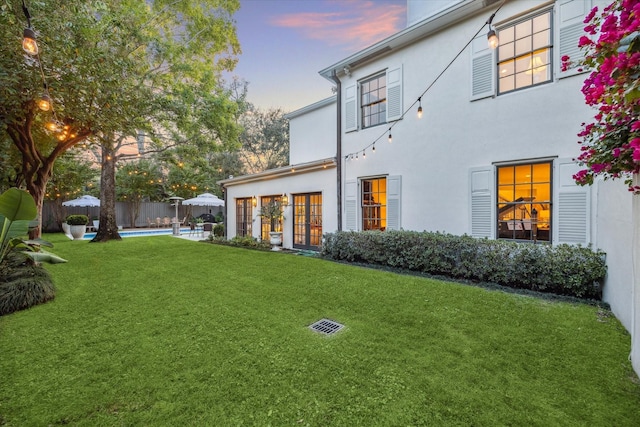 2129 Brentwood Dr, Houston, TX 77019 - back of house at dusk featuring fence, an outdoor pool, stucco siding, french doors, and a lawn