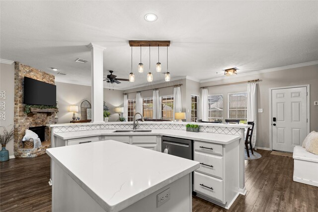 1509 Shamrock Ln, Deer Park, TX 77536 - kitchen with a center island with sink, a sink, open floor plan, crown molding, and a stone fireplace