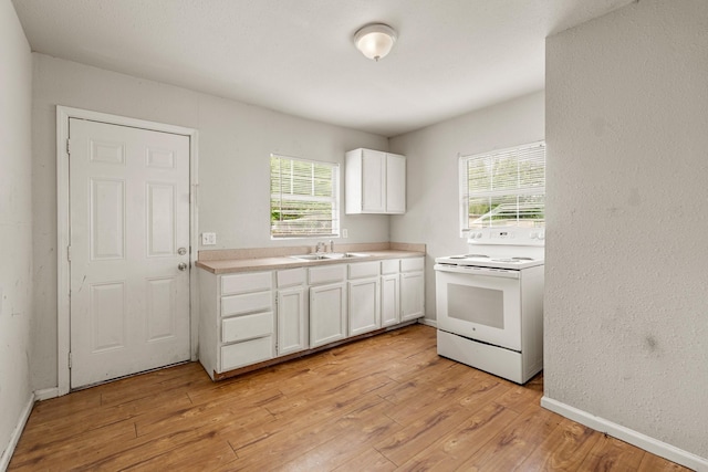 kitchen with white cabinets, plenty of natural light, a sink, and electric stove