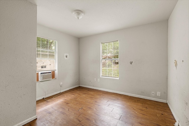 spare room with a healthy amount of sunlight, cooling unit, and hardwood / wood-style floors