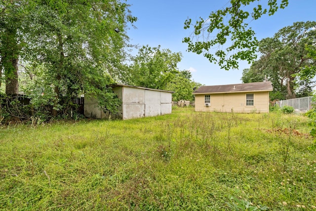 view of yard with fence, a storage unit, and an outdoor structure