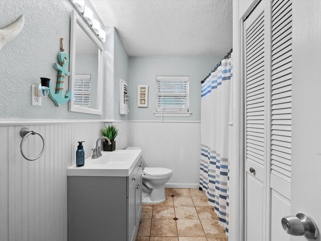 1901 49th St, Galveston, TX 77551 - bathroom with a textured ceiling, toilet, wainscoting, a closet, and vanity