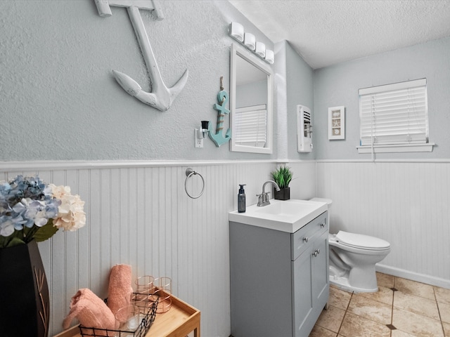 1901 49th St, Galveston, TX 77551 - bathroom featuring tile patterned floors, a wainscoted wall, a textured ceiling, toilet, and vanity