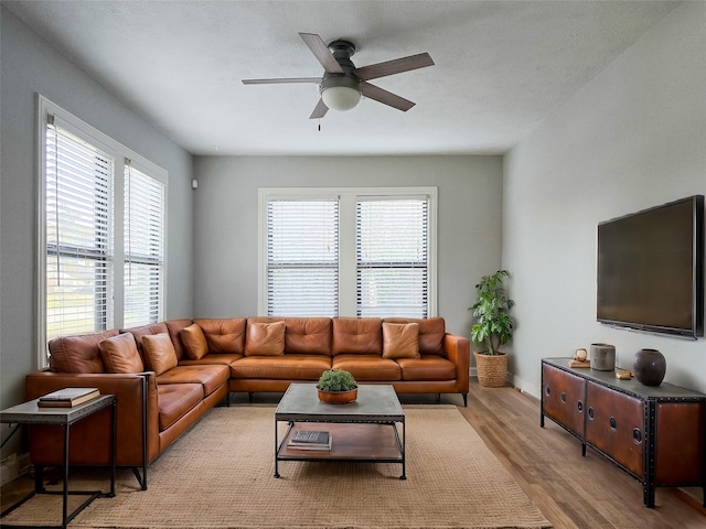 living area with baseboards, a ceiling fan, and wood finished floors