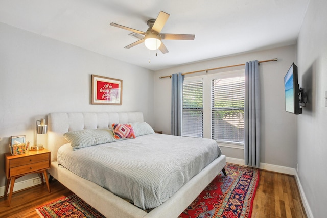 bedroom featuring baseboards, a ceiling fan, a baseboard heating unit, and wood finished floors