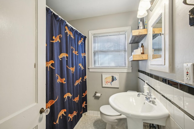 bathroom featuring a shower with shower curtain, tile patterned flooring, toilet, and a sink