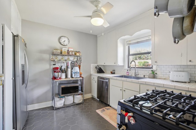 kitchen featuring stainless steel appliances, tasteful backsplash, white cabinets, and a sink