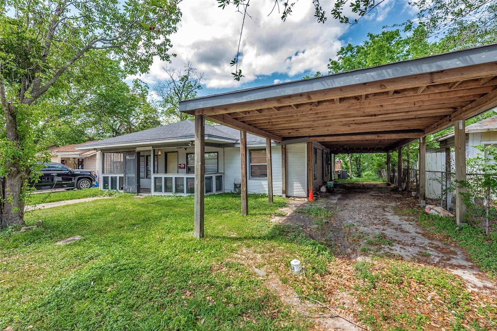 view of parking featuring driveway, a carport, and fence