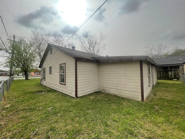 view of home's exterior with a lawn and fence