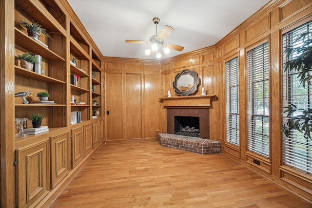 14 Tredington St, Sugar Land, TX 77479 - unfurnished living room with a ceiling fan, a fireplace, light wood-style flooring, and wood walls