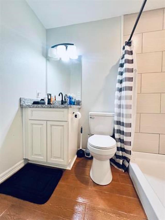 full bathroom featuring toilet, wood finished floors, vanity, and a tile shower