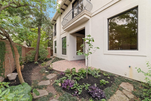 view of home's exterior with stucco siding, a balcony, a patio, and fence