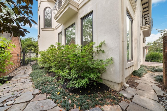 view of side of property with a gate, stucco siding, and fence