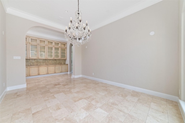 unfurnished dining area featuring arched walkways, ornamental molding, a chandelier, and baseboards
