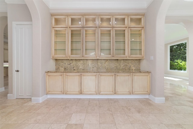 bar with light tile patterned floors, baseboards, arched walkways, and ornamental molding