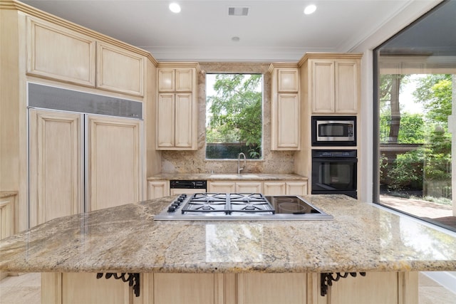 kitchen featuring built in appliances, light brown cabinetry, and a sink