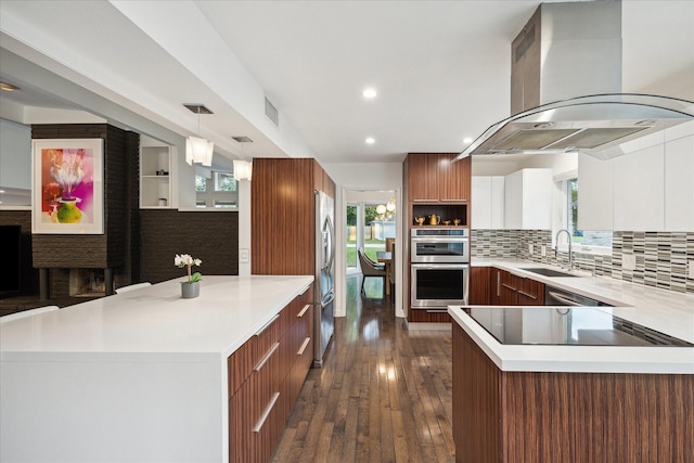 10134 Eddystone Dr, Houston, TX 77043 - kitchen with a sink, island range hood, modern cabinets, a peninsula, and appliances with stainless steel finishes