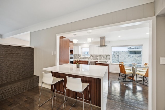 10134 Eddystone Dr, Houston, TX 77043 - kitchen featuring island range hood, a breakfast bar area, appliances with stainless steel finishes, light countertops, and dark wood-style flooring