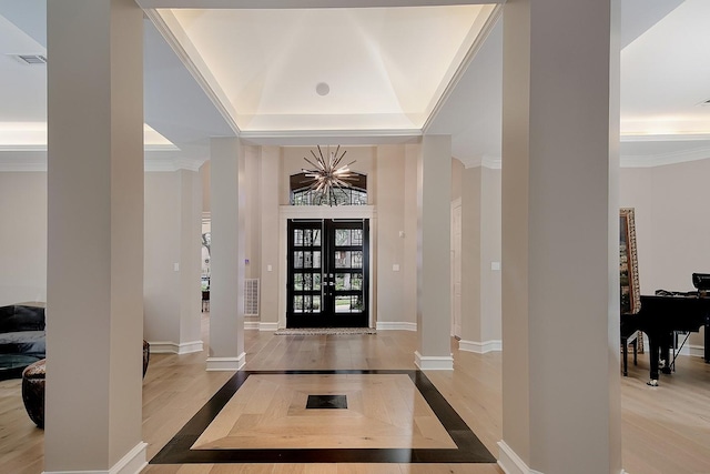 entryway featuring visible vents, decorative columns, a tray ceiling, and wood finished floors