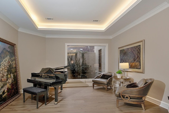 sitting room featuring baseboards, light wood finished floors, visible vents, and a raised ceiling
