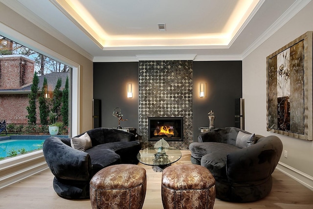 living area with plenty of natural light, wood finished floors, and a raised ceiling