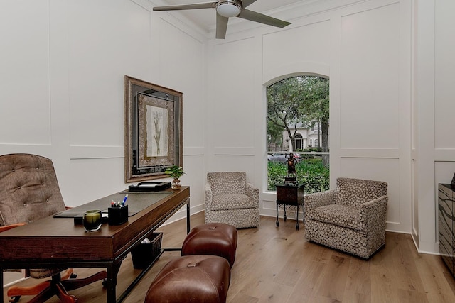 sitting room featuring ceiling fan, a decorative wall, and light wood finished floors