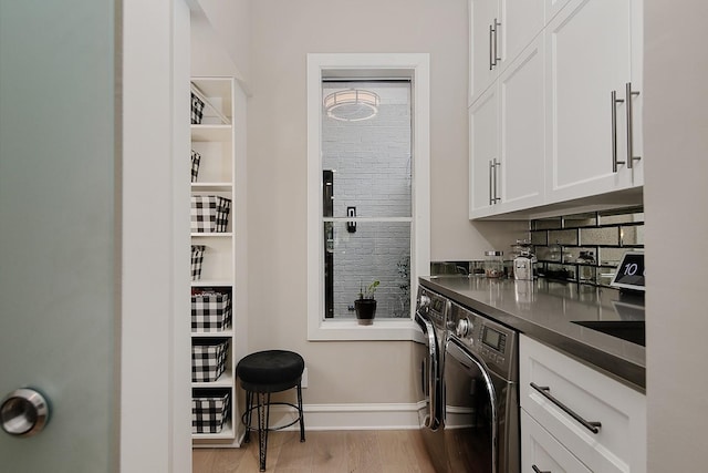 clothes washing area featuring light wood-style floors, washing machine and clothes dryer, and baseboards