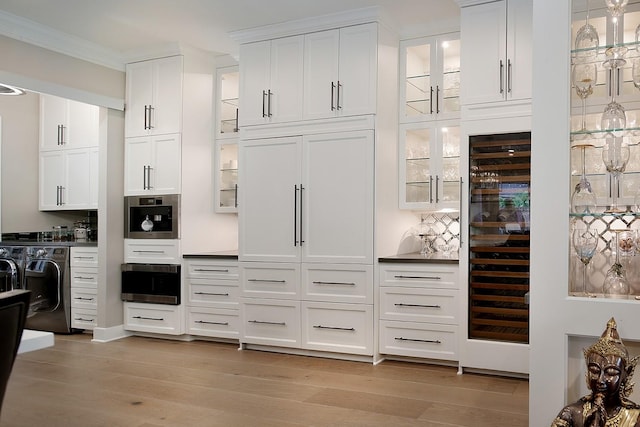 kitchen with oven, glass insert cabinets, white cabinetry, light wood finished floors, and ornamental molding