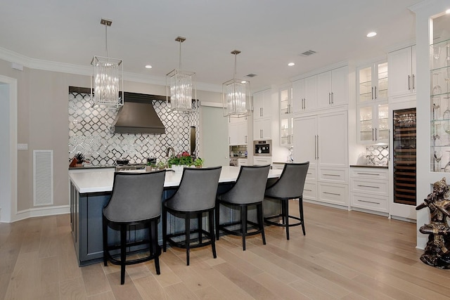 kitchen featuring white cabinets, ventilation hood, visible vents, and backsplash