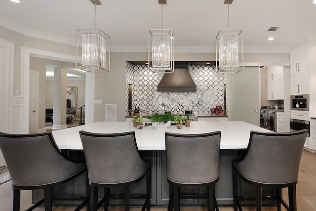 kitchen with a kitchen breakfast bar, decorative backsplash, a large island, white cabinetry, and visible vents