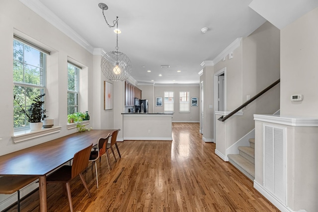 dining room featuring light wood-style flooring, baseboards, recessed lighting, stairs, and crown molding